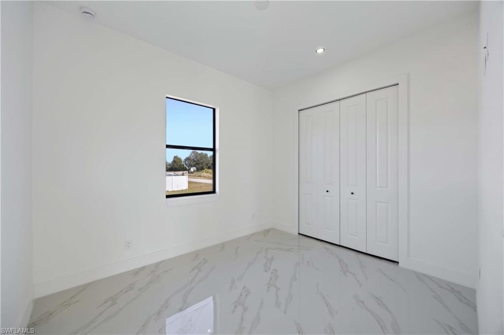 Unfurnished bedroom with a closet, recessed lighting, and light marble finish flooring