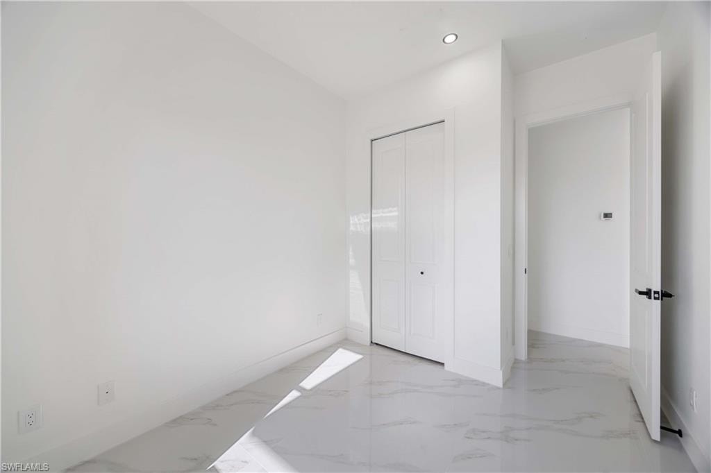 Unfurnished bedroom featuring recessed lighting, a closet, and light marble finish floors