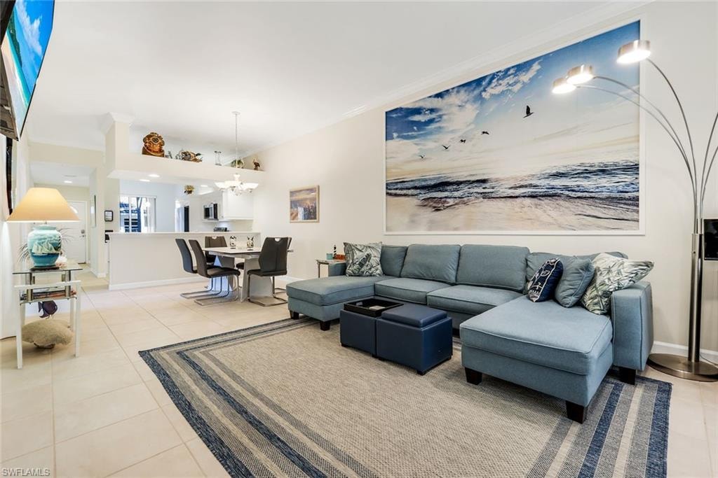 Living room with light tile patterned flooring, crown molding looking into dining area and open kitchen.