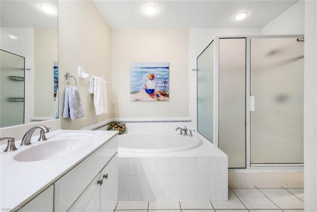 Primary bathroom featuring a bath, vanity, a shower stall, and light tile patterned flooring.