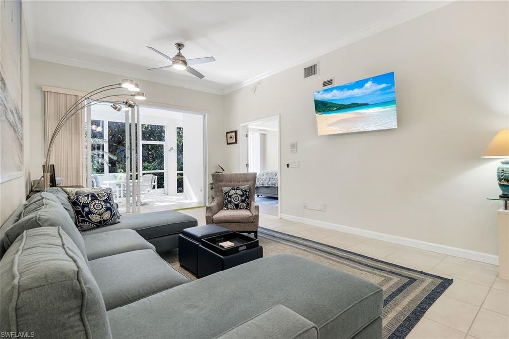 Living room with crown molding, light tile patterned floors with view into Lanai and entrance to Primary bedroom.