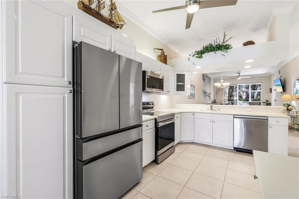 Kitchen featuring stainless steel appliances, ornamental molding, white cabinetry, and light Corian countertops.