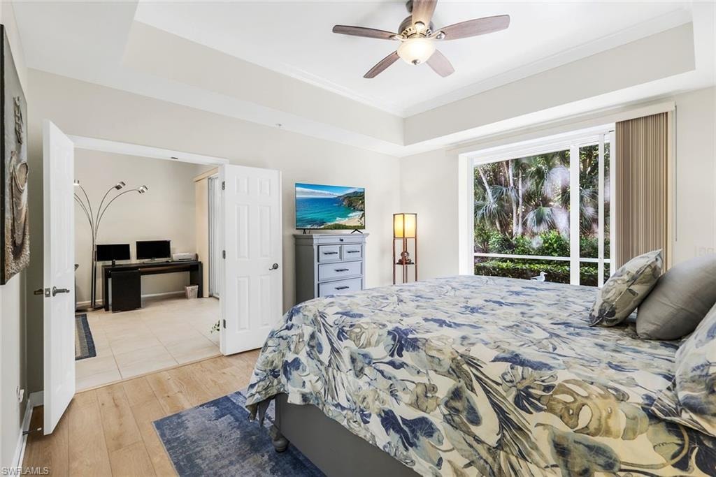 Primary Bedroom with a raised ceiling, light wood-type tile flooring looking onto rear lanai.
