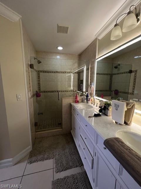 Full bath with double vanity, light tile patterned flooring, and a stall shower
