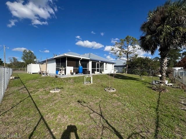 Rear view of house featuring a fenced backyard, a sunroom, and a patio area