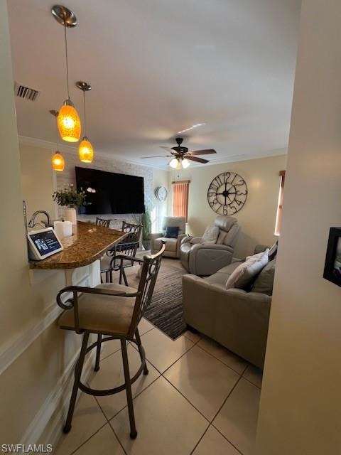 Living room featuring light tile patterned floors, crown molding, and a ceiling fan