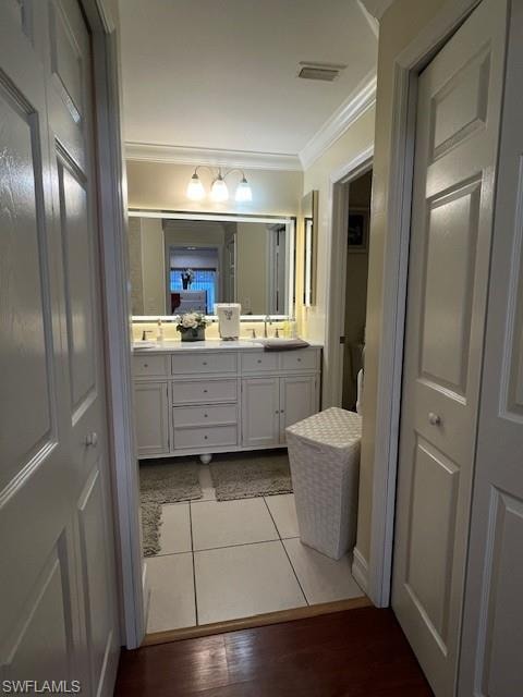 Bathroom featuring double vanity, a closet, ornamental molding, and light wood-type flooring