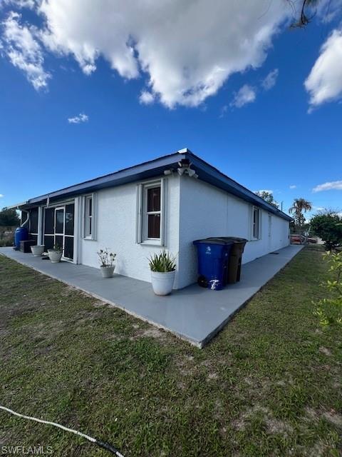 View of side of property with a yard and stucco siding