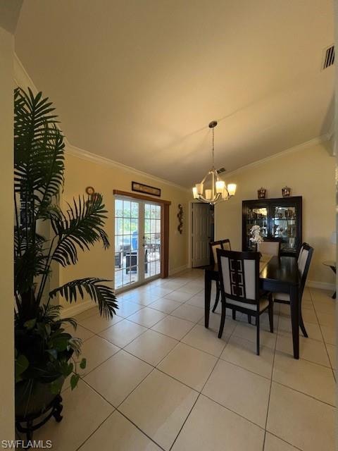 Dining space featuring ornamental molding, suspended lighting, light tile patterned flooring, vaulted ceiling, and french doors