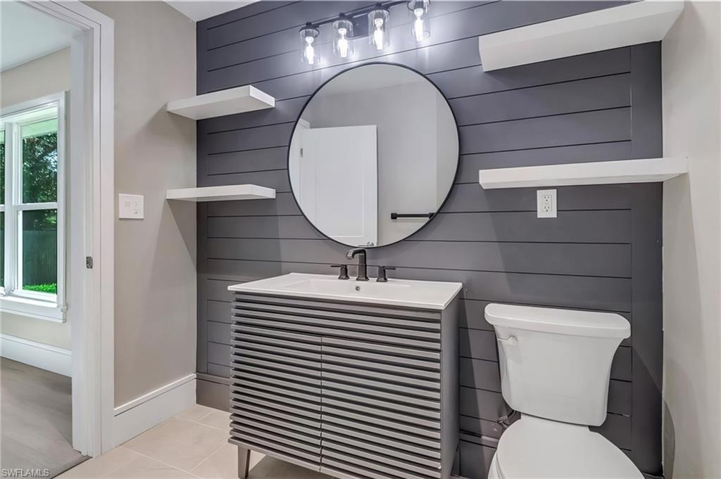 Bathroom featuring vanity, light tile patterned flooring, and wooden walls