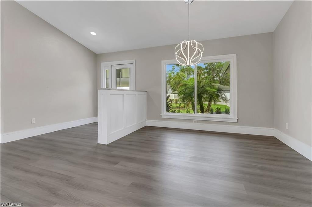 Unfurnished dining area with healthy amount of natural light, hanging lights, and dark wood-style flooring