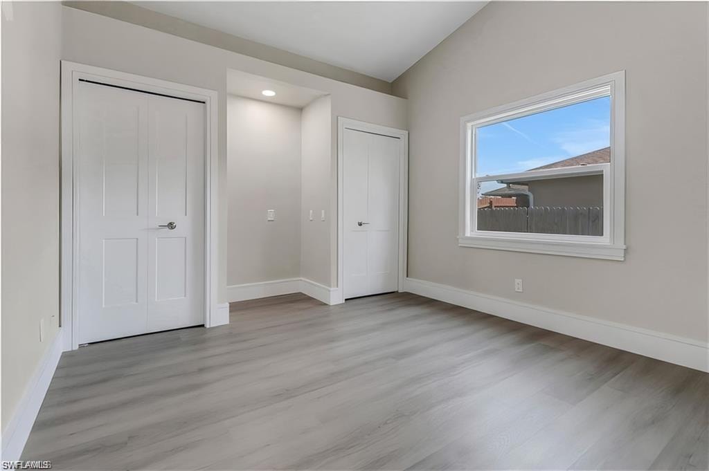 Unfurnished bedroom with lofted ceiling and light wood-style floors