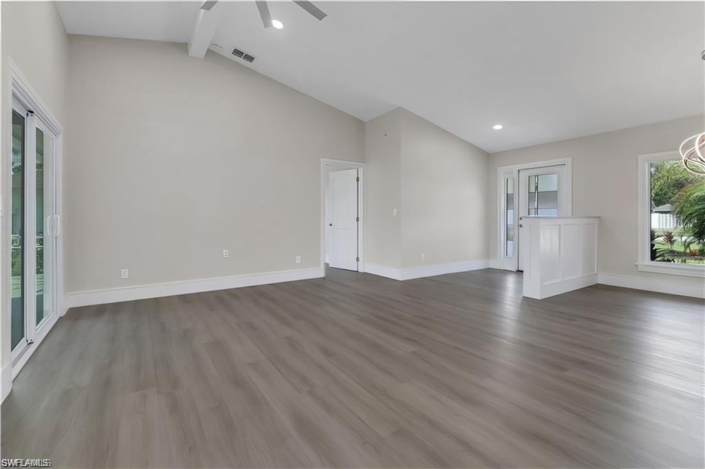 Unfurnished living room featuring lofted ceiling, dark wood-style floors, a ceiling fan, and a chandelier