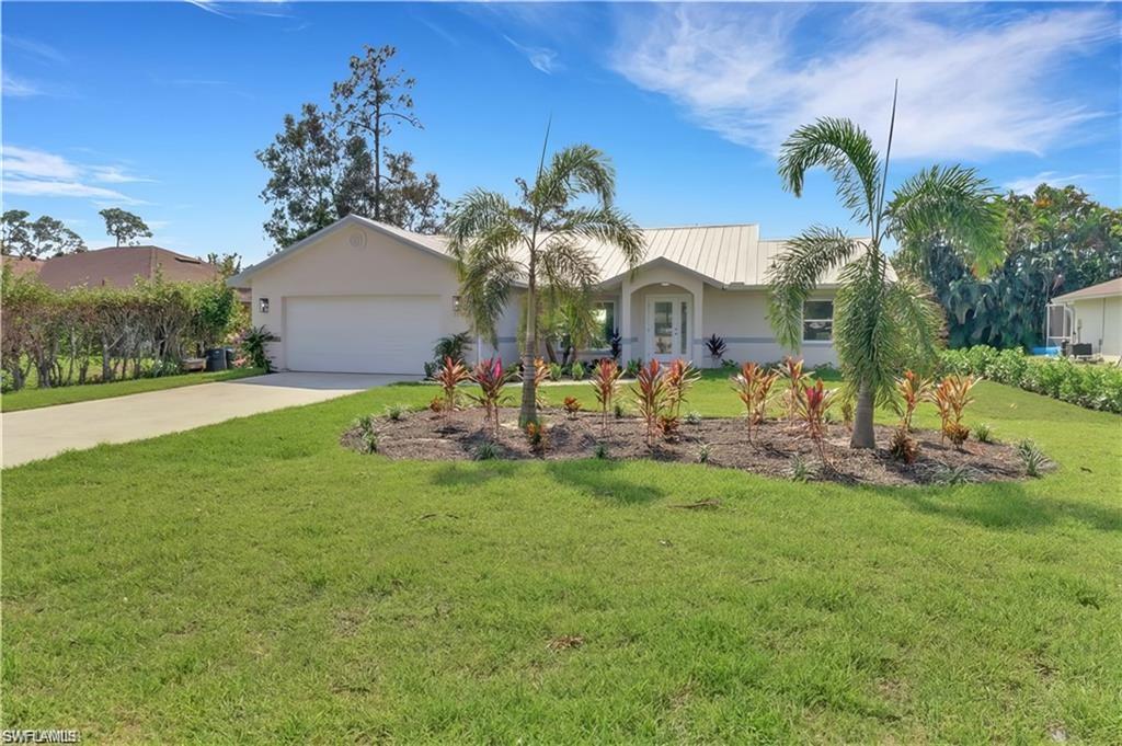 Ranch-style home featuring driveway, a garage, a front yard, and stucco siding