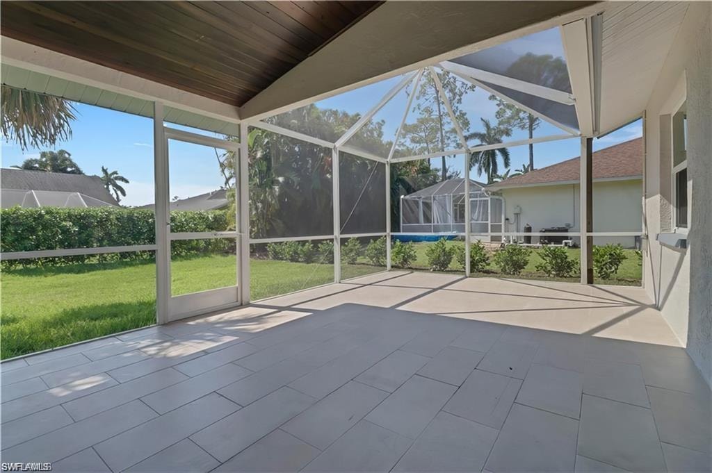 Unfurnished sunroom with a patio and lofted ceiling