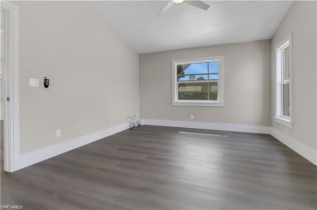 Spare room with a ceiling fan, dark wood-style flooring, and a vaulted wood ceiling