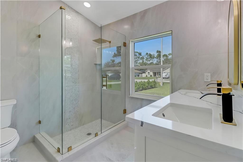 Bathroom with double vanity, a shower stall, and tile walls
