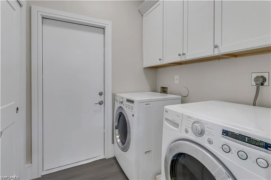 Laundry room featuring washer and dryer, dark wood-style floors, and cabinet space