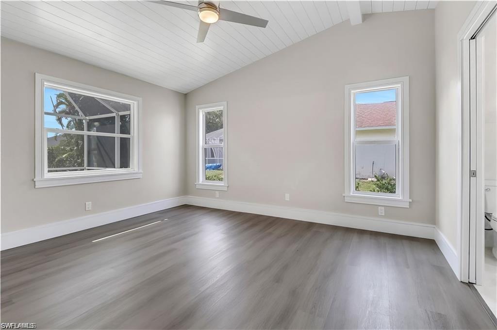 Spare room featuring a ceiling fan, a vaulted wood ceiling, and dark wood finished floors