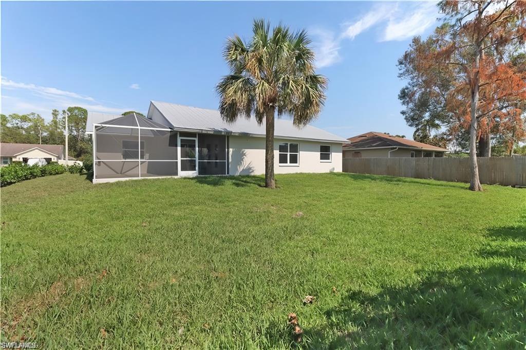 Rear view of house with a yard, a sunroom, and stucco siding