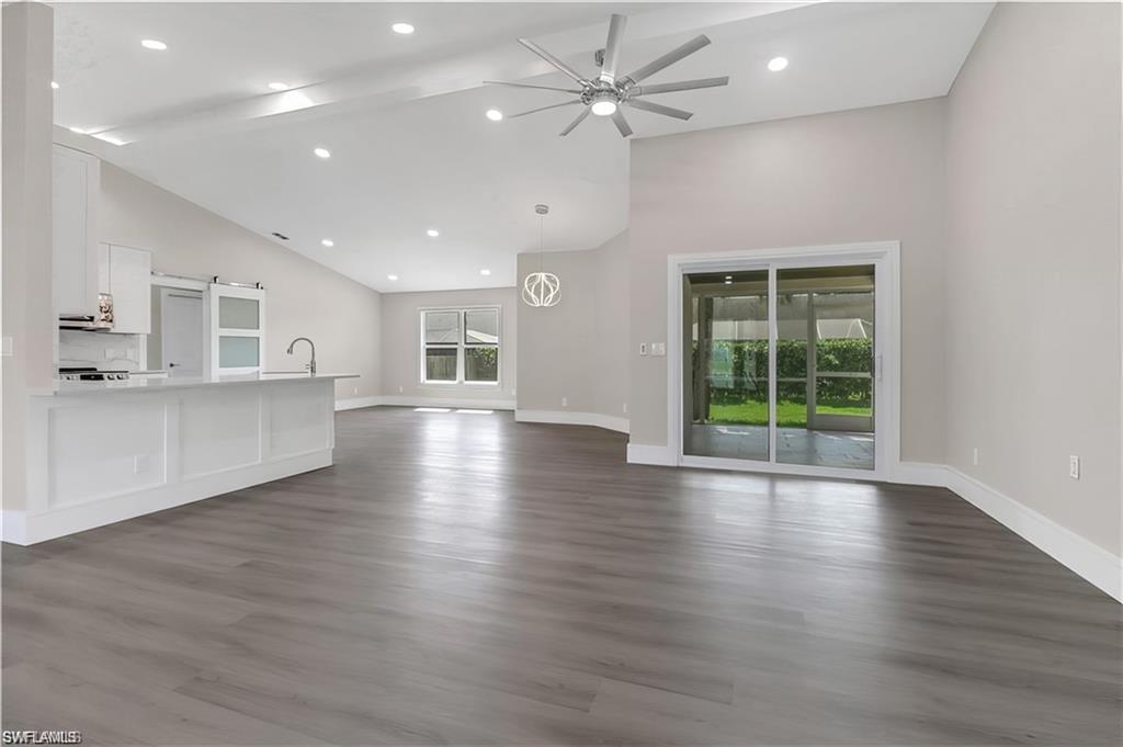 Unfurnished living room with a ceiling fan, recessed lighting, vaulted ceiling, and dark wood-style floors