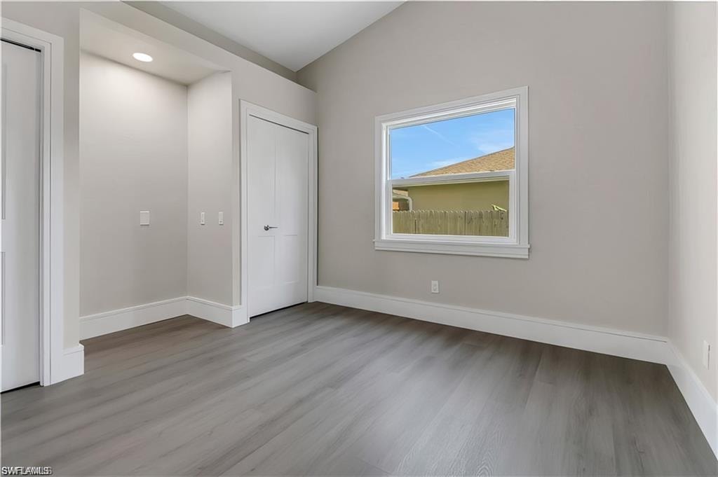 Unfurnished bedroom with light wood-style flooring, vaulted ceiling, and recessed lighting