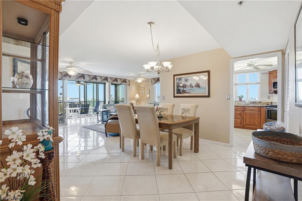 Dining area featuring ceiling fan, hanging lights, light tile patterned flooring, and healthy amount of natural light - Virtually Edited Image
