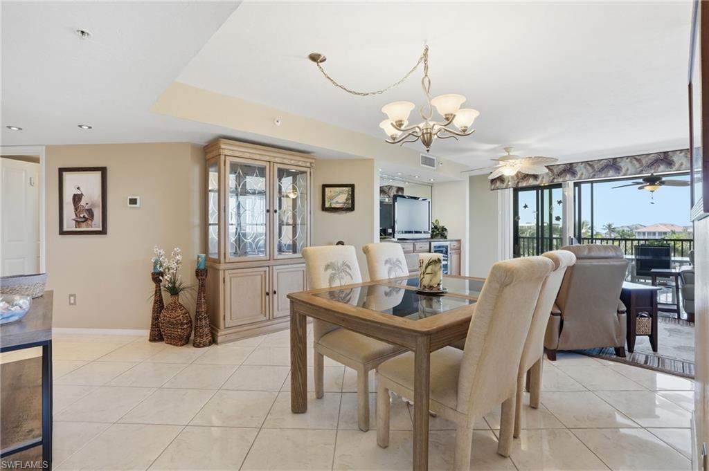 Dining room featuring a chandelier, a ceiling fan, and light tile patterned floors - Virtually Edited Image