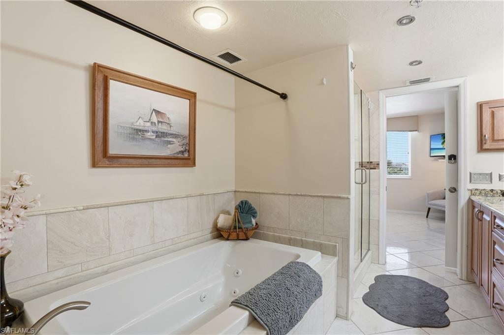Full bath with vanity, a stall shower, a whirlpool tub, and light tile patterned flooring - Virtually Edited Image