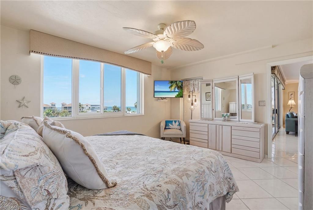 Bedroom with a ceiling fan and light tile patterned floors - Virtually Edited Image