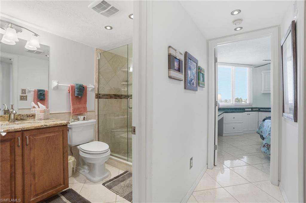 Ensuite bathroom featuring light tile patterned floors, vanity, and a stall shower - Virtually Edited Image