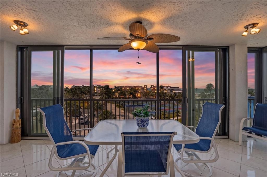 Tiled dining area featuring a ceiling fan, a textured ceiling, and floor to ceiling windows - Virtually Edited Image