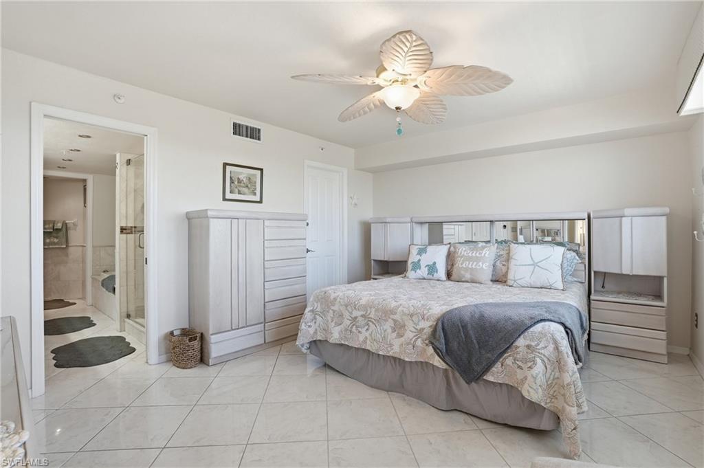 Bedroom featuring ceiling fan, light tile patterned floors, and ensuite bath - Virtually Edited Image