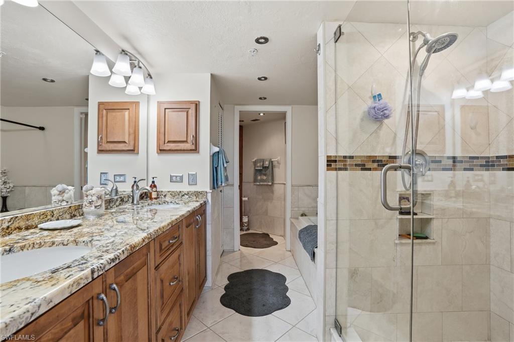 Bathroom with double vanity, a stall shower, light tile patterned flooring, and tile walls - Virtually Edited Image