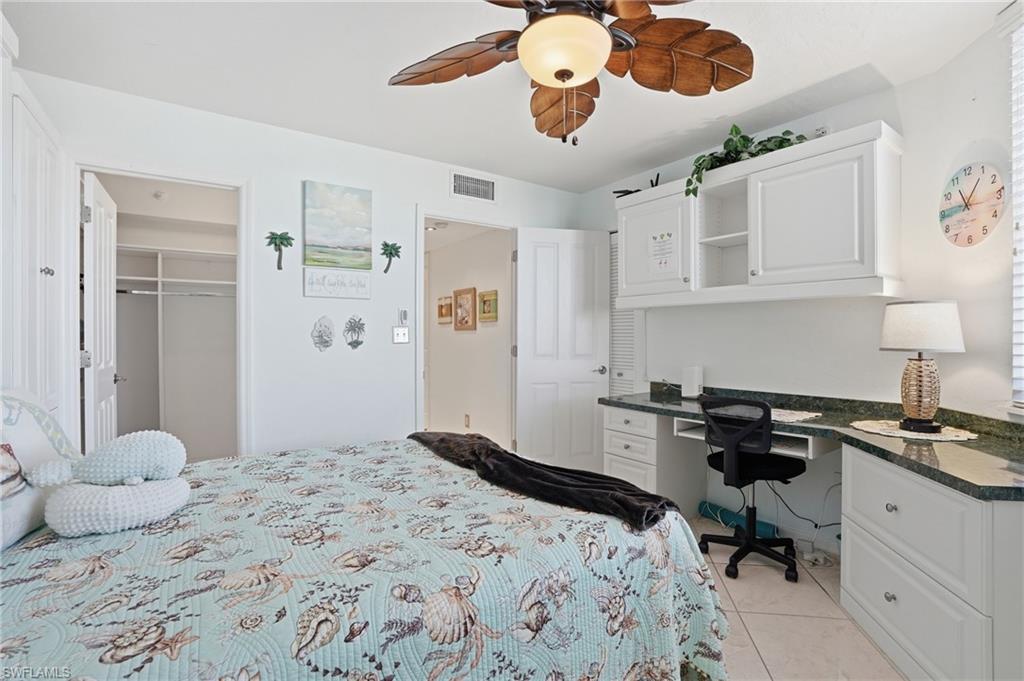 Bedroom featuring built in desk, a walk in closet, light tile patterned floors, and ceiling fan - Virtually Edited Image