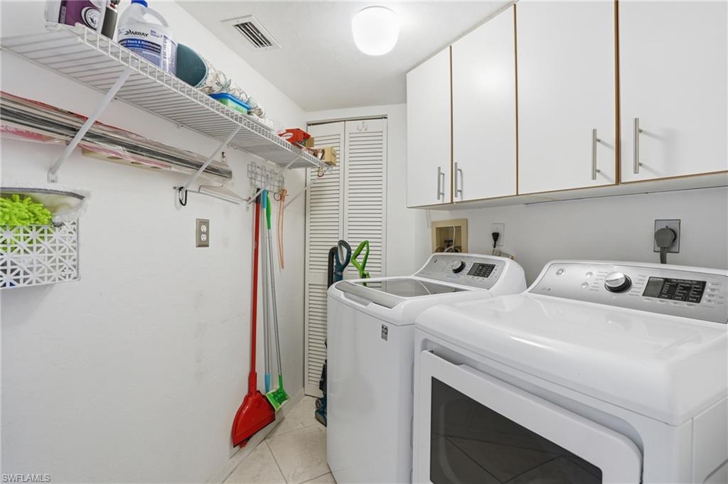 Laundry area with cabinet space, independent washer and dryer, and light tile patterned floors - Virtually Edited Image