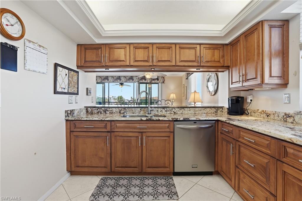 Kitchen featuring wood finish cabinetry, light stone counters, and ornamental molding - Virtually Edited Image