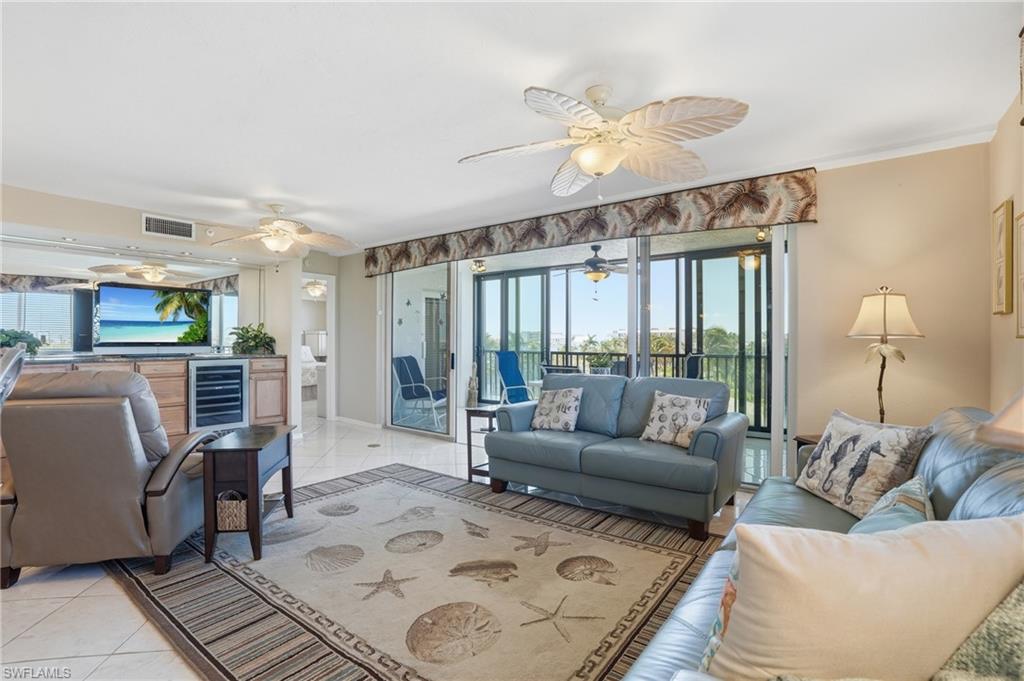 Living area featuring healthy amount of natural light, light tile patterned floors, wine cooler, and ornamental molding - Virtually Edited Image