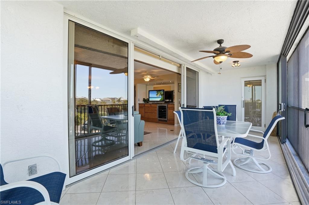 Sunroom / solarium with outdoor dining space, a ceiling fan, and beverage cooler - Virtually Edited Image
