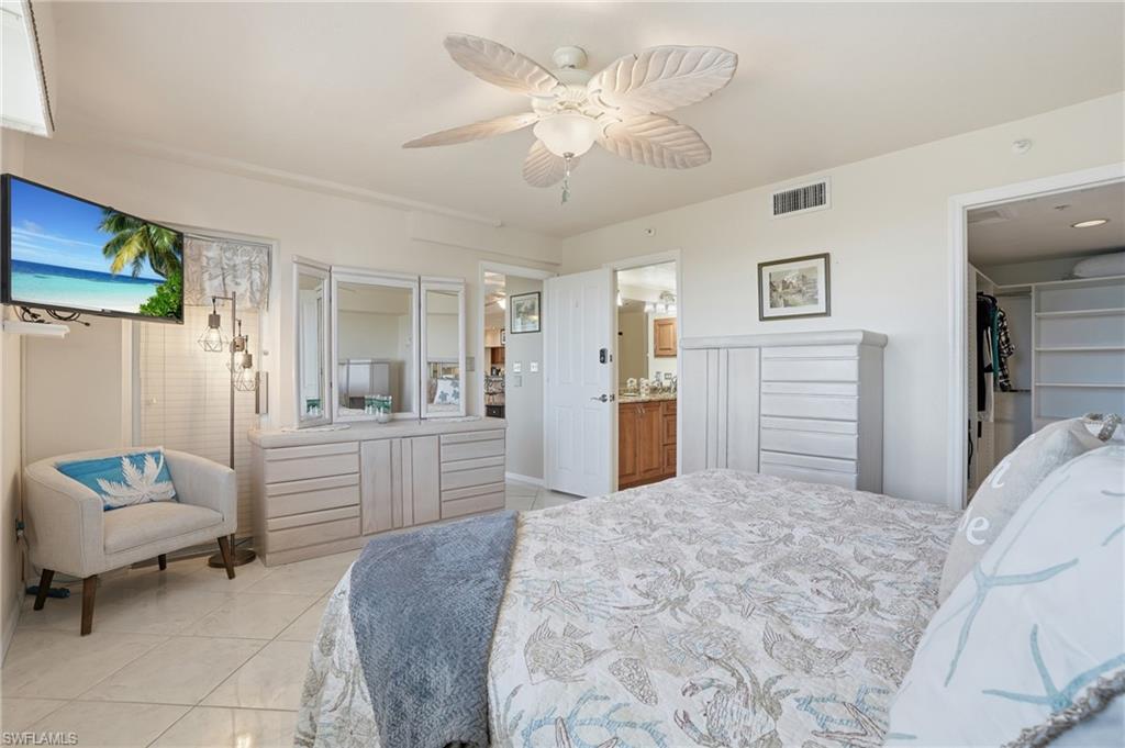 Bedroom featuring light tile patterned flooring, ceiling fan, and a walk in closet - Virtually Edited Image