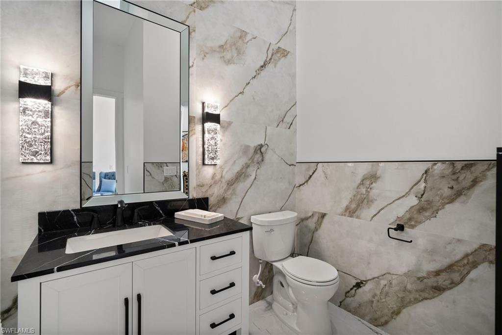 Bathroom with vanity, tile walls, and toilet