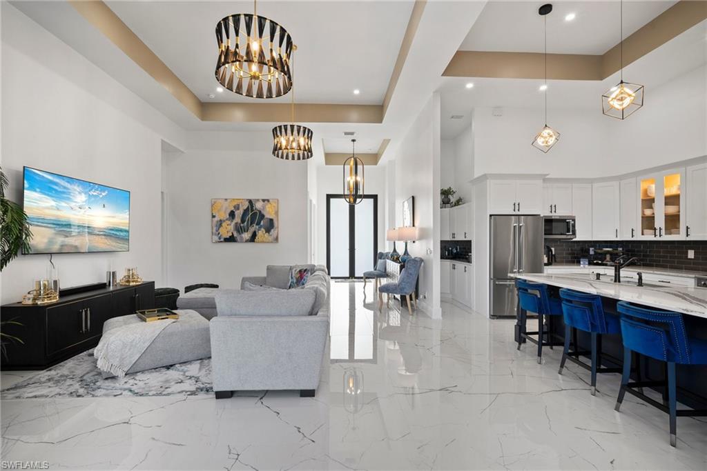 Living room with a tray ceiling, a towering ceiling, and a notable chandelier