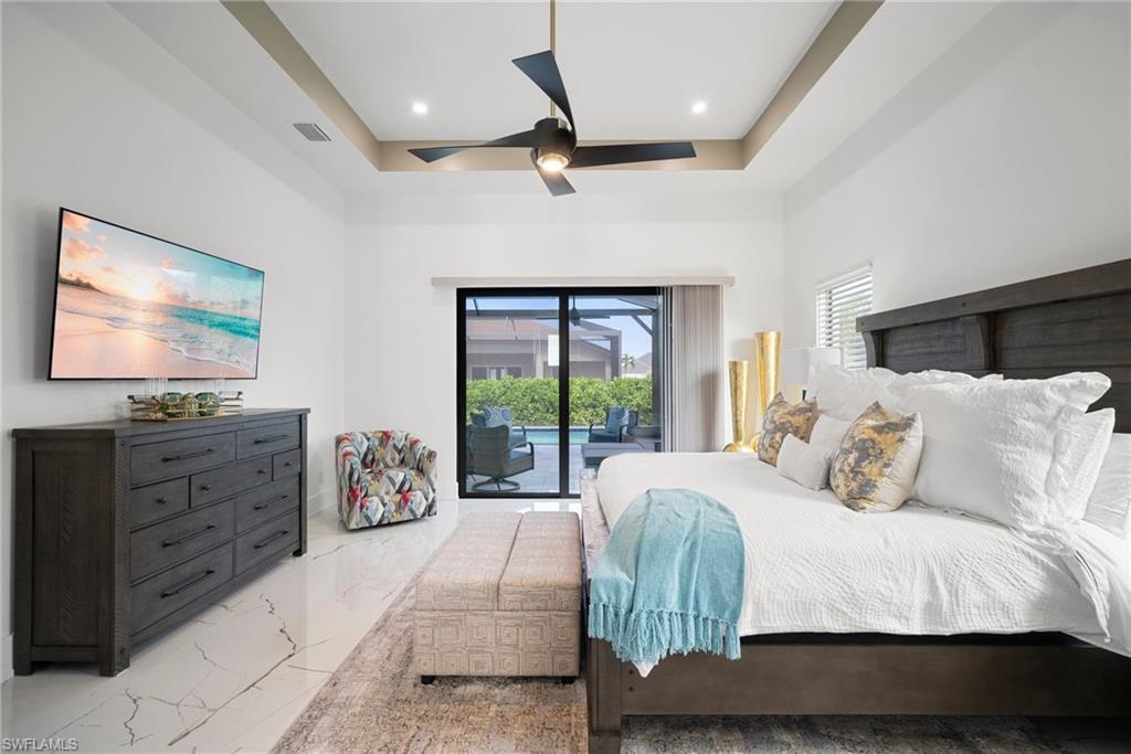 Bedroom with a raised ceiling, ceiling fan, and access to exterior