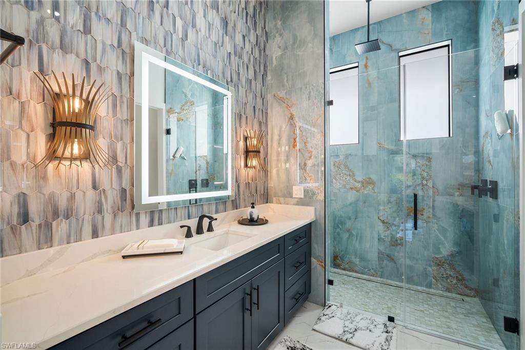 Bathroom with vanity, a shower with door, and tile walls