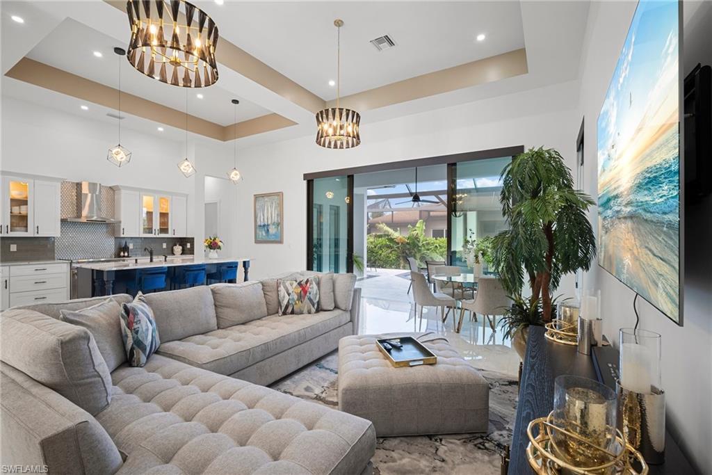 Living room with a notable chandelier, sink, and a tray ceiling