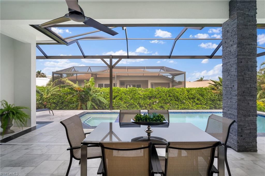 View of patio with a lanai and a pool with hot tub
