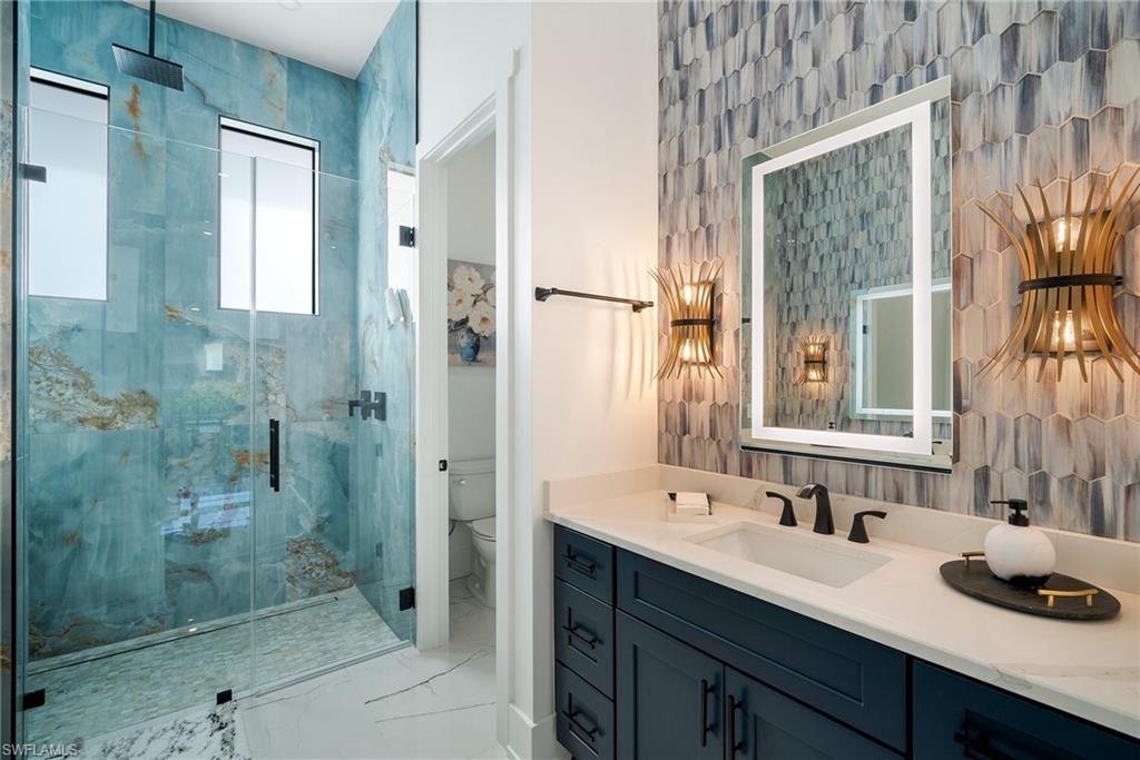 Bathroom featuring vanity, toilet, and a shower with door