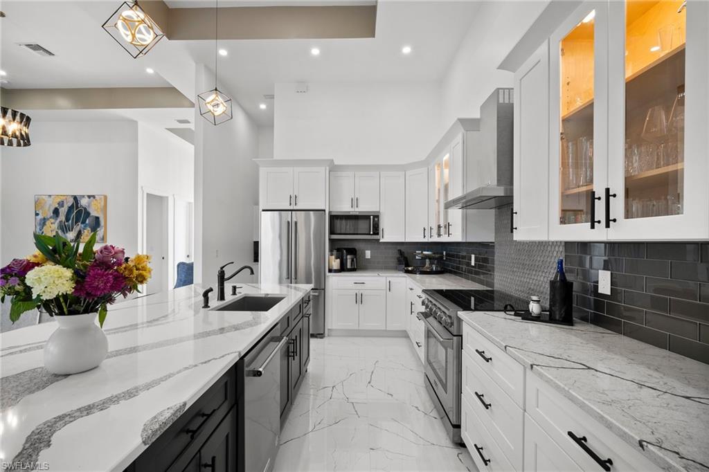 Kitchen featuring white cabinets, pendant lighting, high quality appliances, and sink