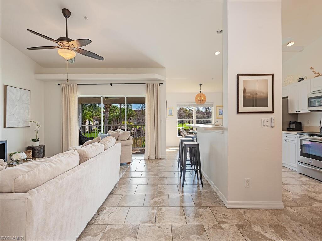 Living area featuring a ceiling fan, light stone finish flooring.