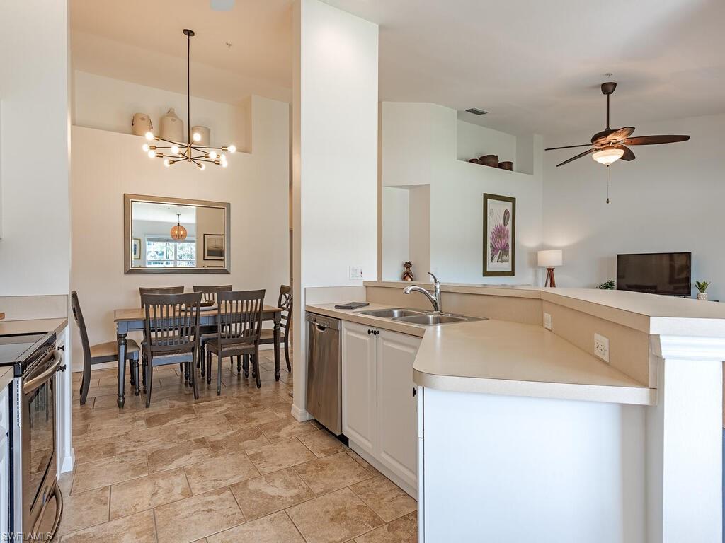 Kitchen featuring light countertops, a ceiling fan, suspended lighting, stainless steel appliances, and open floor plan